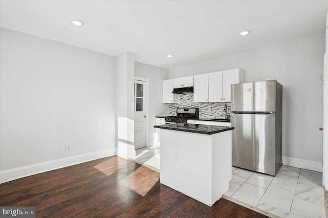 kitchen featuring white cabinets, appliances with stainless steel finishes, a kitchen island, decorative backsplash, and sink