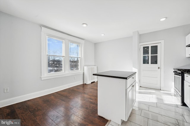 kitchen with white cabinets, hardwood / wood-style floors, stainless steel range with gas cooktop, and a center island