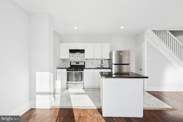 kitchen with white cabinets, appliances with stainless steel finishes, dark stone counters, decorative backsplash, and sink