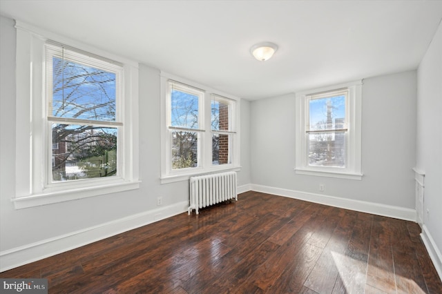 spare room with dark hardwood / wood-style floors and radiator