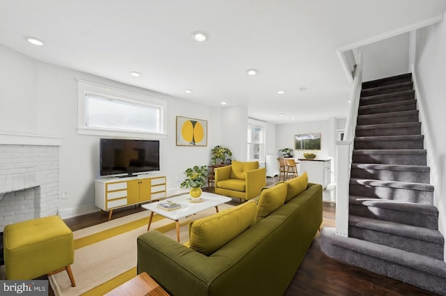 living room featuring a brick fireplace and wood-type flooring