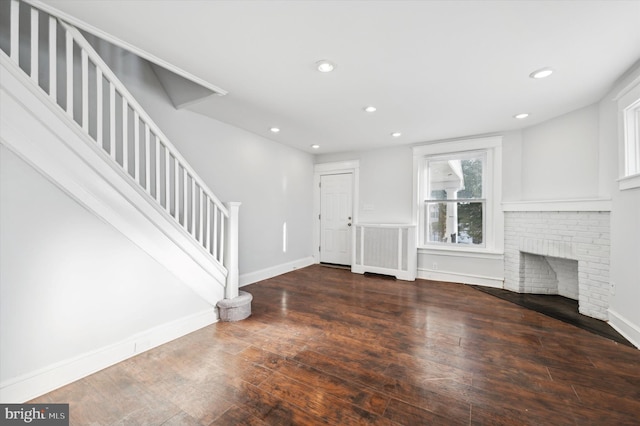 unfurnished living room featuring dark hardwood / wood-style floors, radiator heating unit, and a fireplace