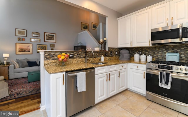 kitchen with dark stone countertops, decorative backsplash, sink, white cabinetry, and stainless steel appliances