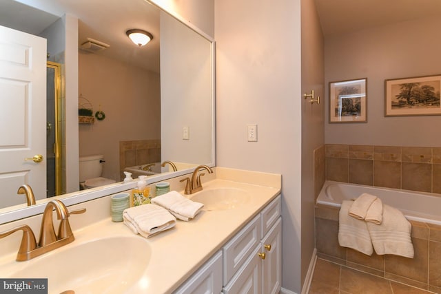 bathroom featuring toilet, tile patterned floors, tiled tub, and vanity