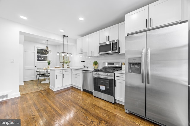 kitchen with decorative light fixtures, decorative backsplash, sink, appliances with stainless steel finishes, and white cabinets