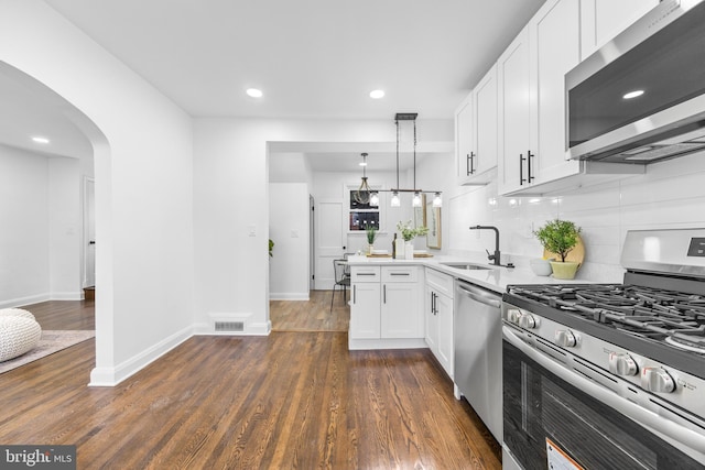 kitchen featuring appliances with stainless steel finishes, dark hardwood / wood-style floors, decorative light fixtures, white cabinets, and sink