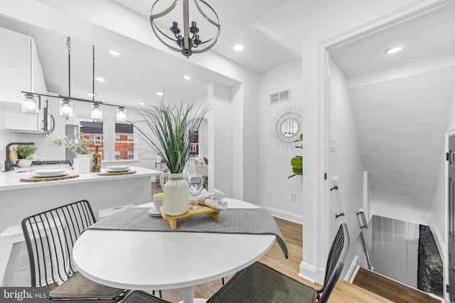 dining room with sink, a chandelier, and light wood-type flooring