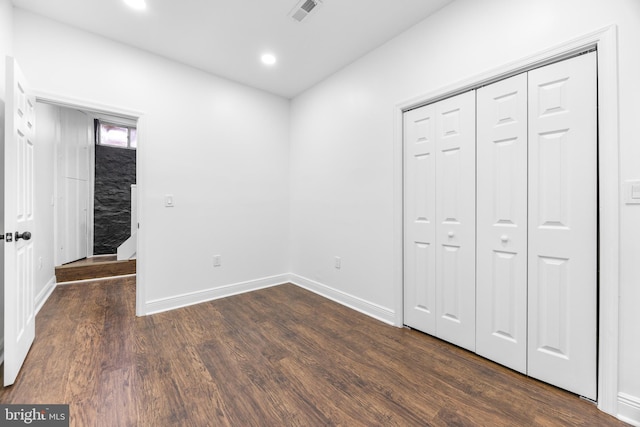 unfurnished bedroom featuring a closet and dark hardwood / wood-style flooring