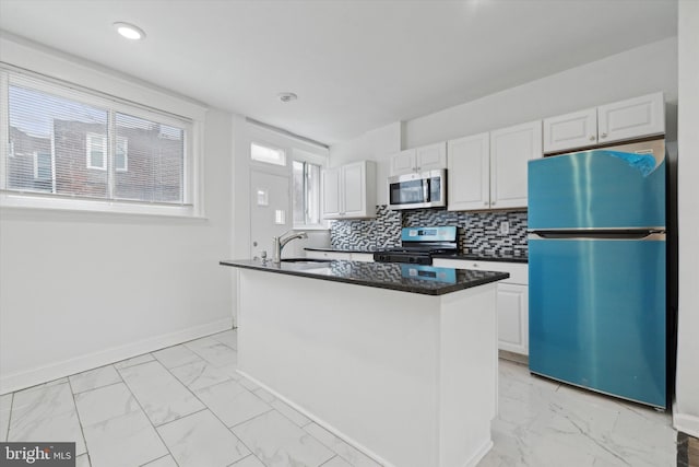 kitchen with sink, appliances with stainless steel finishes, an island with sink, decorative backsplash, and white cabinets