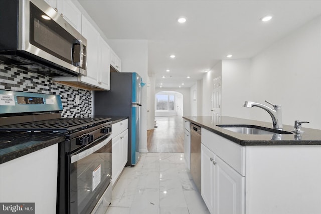 kitchen featuring stainless steel appliances, white cabinetry, sink, and an island with sink