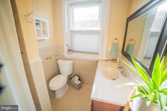 bathroom featuring toilet, tile patterned flooring, vanity, and tile walls