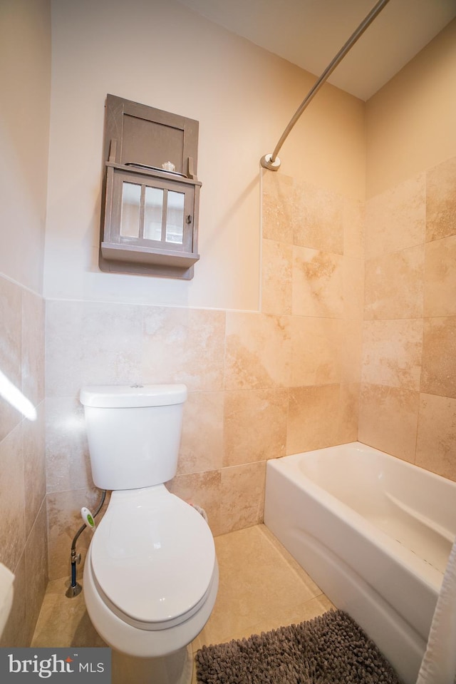 bathroom featuring tile walls, shower / washtub combination, tile patterned flooring, and toilet