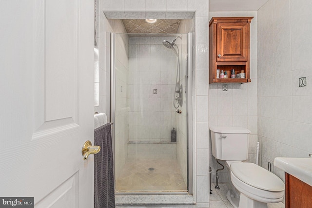 bathroom with toilet, tile walls, tile patterned floors, an enclosed shower, and vanity