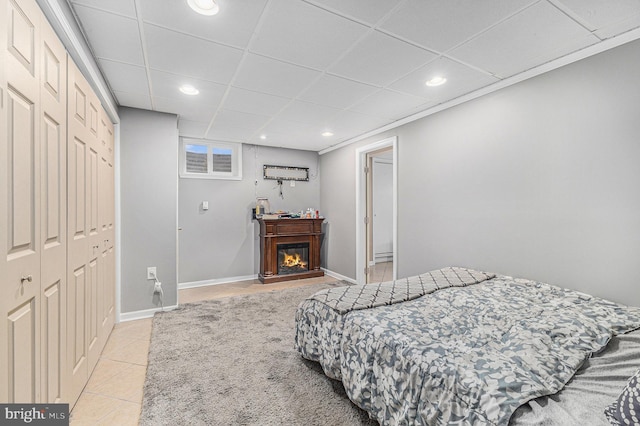 bedroom with a drop ceiling, a closet, and light tile patterned flooring