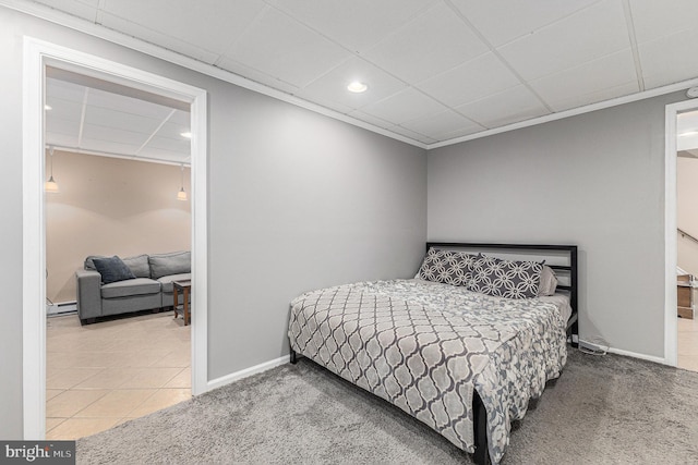 tiled bedroom featuring a baseboard radiator, a drop ceiling, and ornamental molding