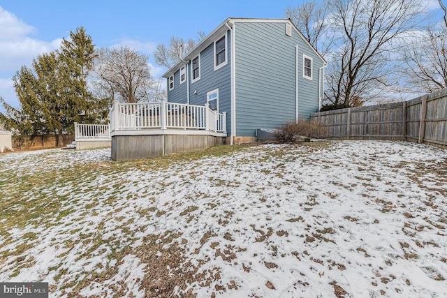 snow covered back of property featuring a wooden deck