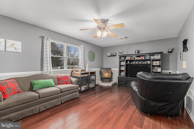 living room with ceiling fan, dark hardwood / wood-style flooring, and a wood stove