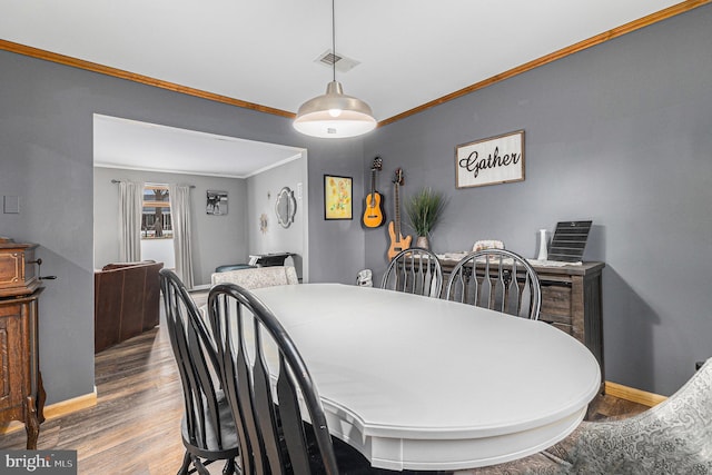 dining room with wood-type flooring and crown molding