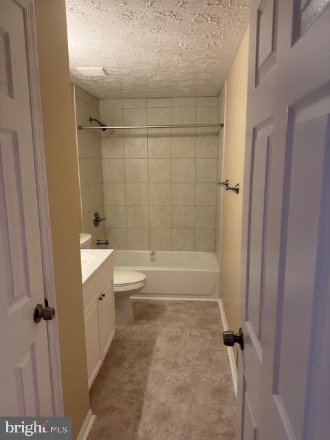 full bathroom featuring a textured ceiling, vanity, toilet, and tiled shower / bath