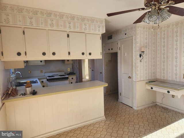 kitchen featuring kitchen peninsula, ceiling fan, white gas range oven, and sink