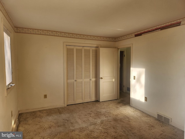 unfurnished bedroom featuring light carpet and a closet