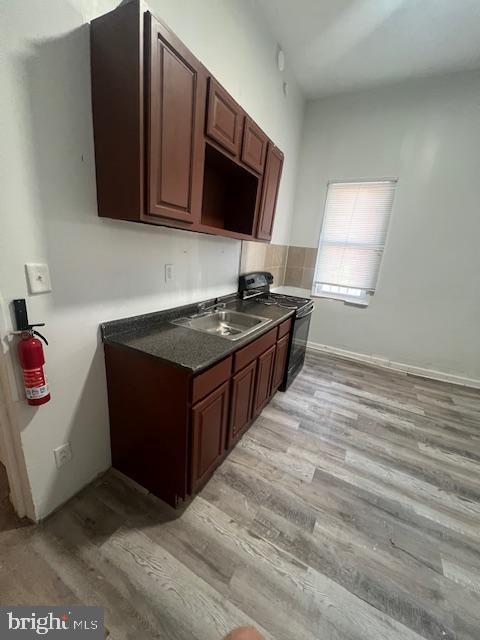 kitchen with light hardwood / wood-style floors, sink, and black range oven