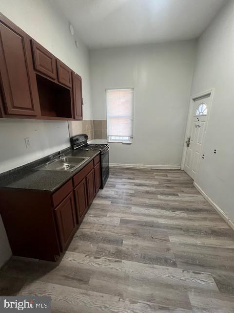 kitchen with black / electric stove, dark brown cabinetry, sink, and light hardwood / wood-style flooring