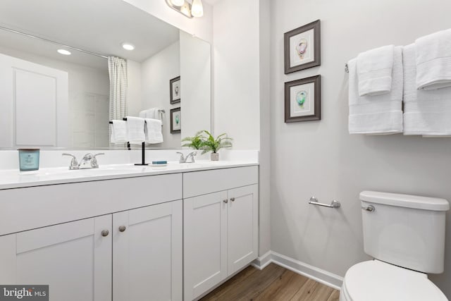 bathroom with wood-type flooring, vanity, and toilet