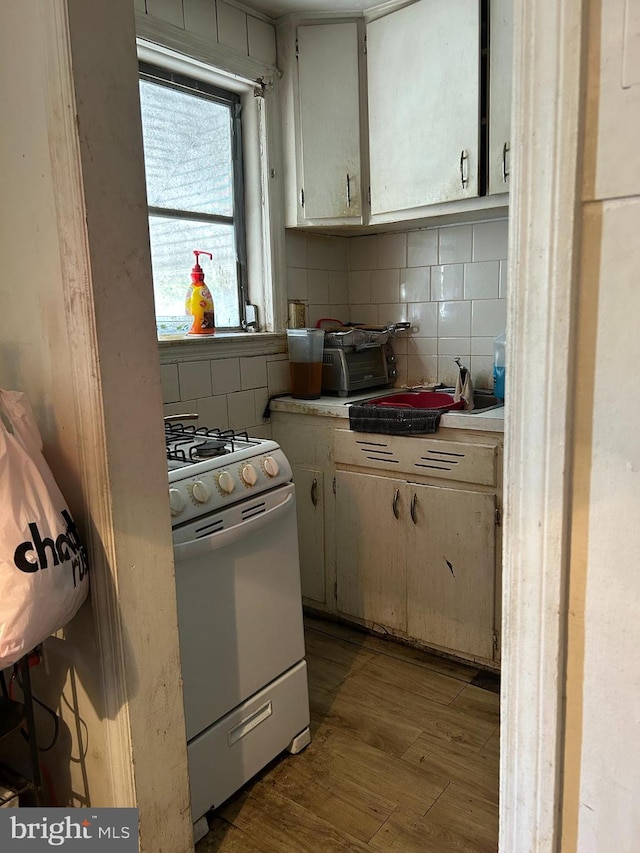 kitchen featuring light wood-type flooring, backsplash, and white gas stove