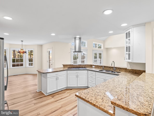 kitchen featuring sink, white cabinetry, light stone counters, kitchen peninsula, and island range hood