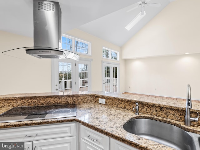 kitchen featuring electric cooktop, sink, white cabinets, vaulted ceiling, and island exhaust hood