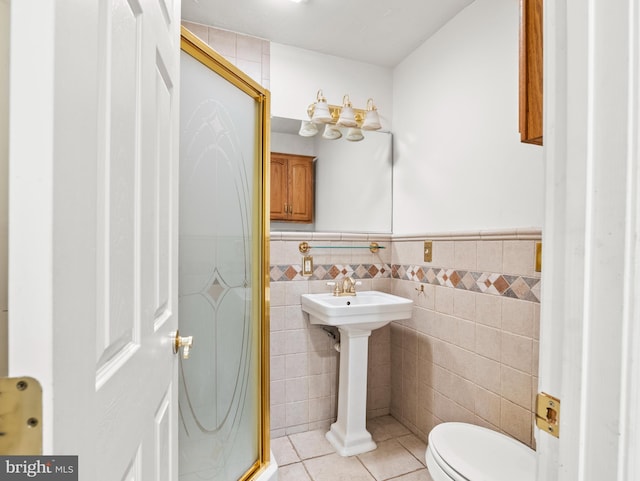 bathroom with tile walls, a shower with shower door, tile patterned floors, and toilet