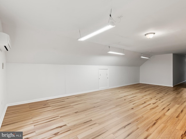 bonus room with light wood-type flooring, lofted ceiling, and an AC wall unit