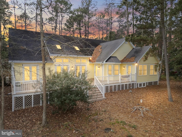 back house at dusk featuring a deck