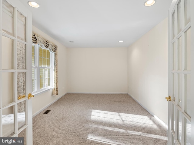 carpeted spare room featuring french doors