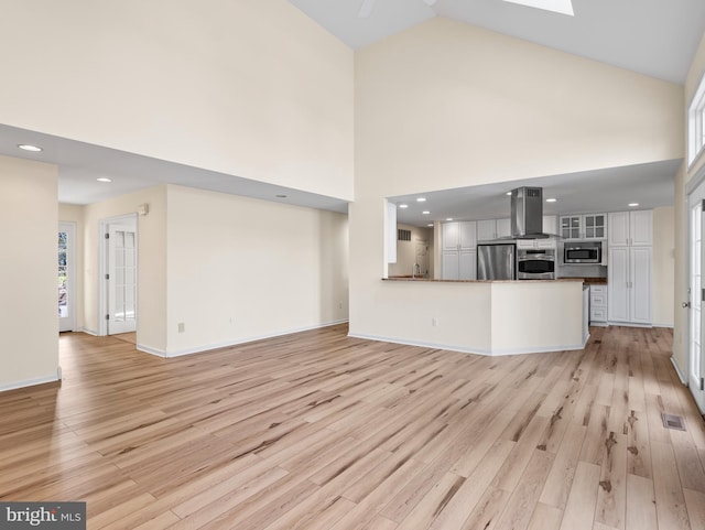 unfurnished living room featuring high vaulted ceiling and light hardwood / wood-style flooring