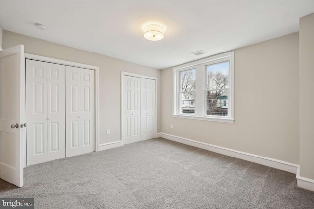 unfurnished bedroom with carpet floors and multiple closets