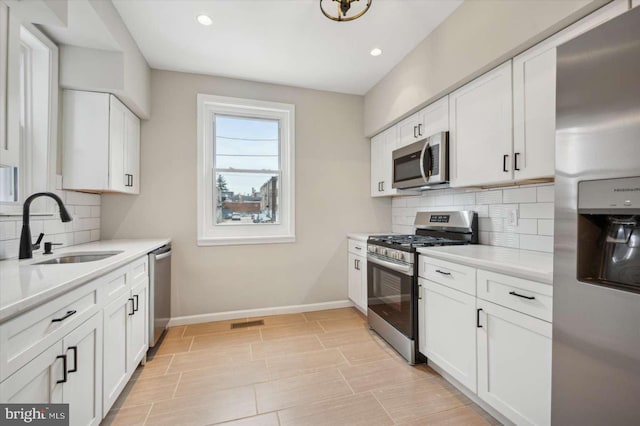 kitchen featuring tasteful backsplash, sink, white cabinets, and stainless steel appliances