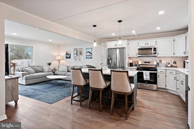 kitchen with backsplash, stainless steel appliances, pendant lighting, light hardwood / wood-style floors, and white cabinetry