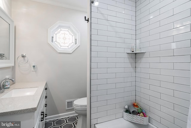 bathroom featuring tile patterned floors, crown molding, vanity, and toilet