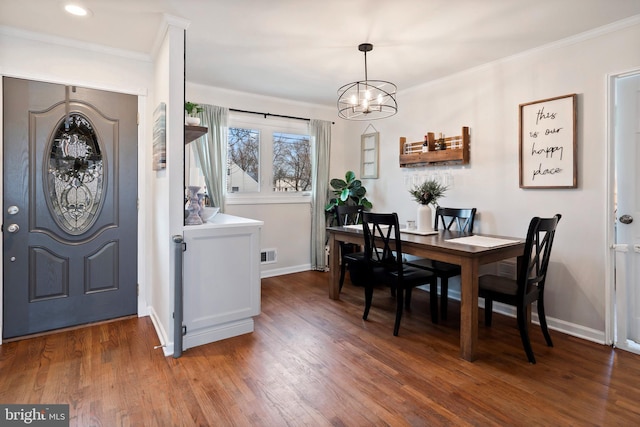 dining room with crown molding, dark wood-type flooring, and a chandelier