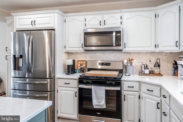 kitchen with white cabinets, decorative backsplash, crown molding, and appliances with stainless steel finishes