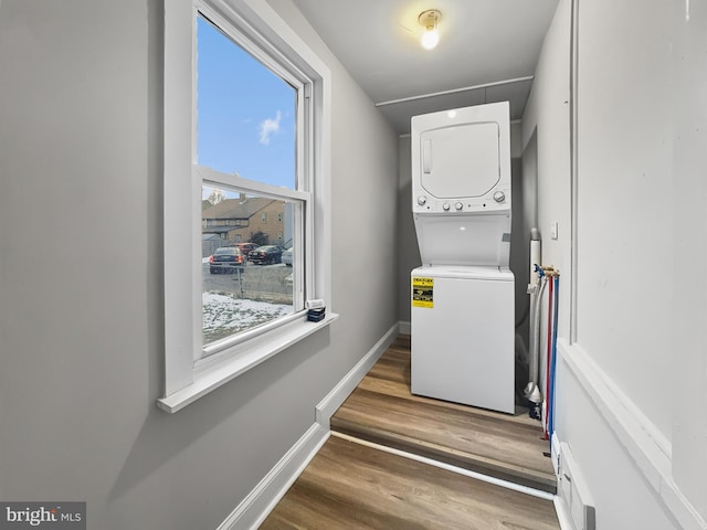 laundry room featuring stacked washer and dryer and wood-type flooring