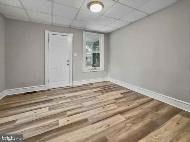 unfurnished room featuring hardwood / wood-style flooring and a paneled ceiling