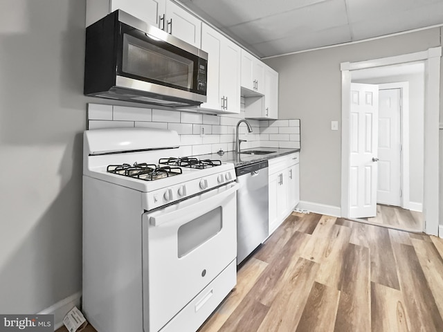 kitchen with decorative backsplash, white cabinetry, sink, and stainless steel appliances