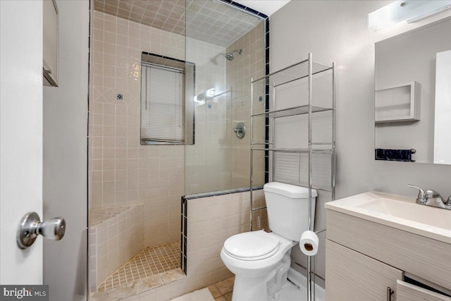 bathroom with tiled shower, tile patterned flooring, vanity, and toilet