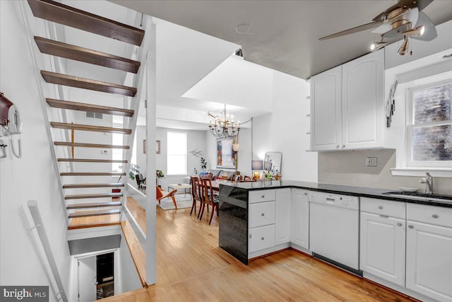 kitchen featuring pendant lighting, ceiling fan with notable chandelier, white dishwasher, white cabinetry, and sink