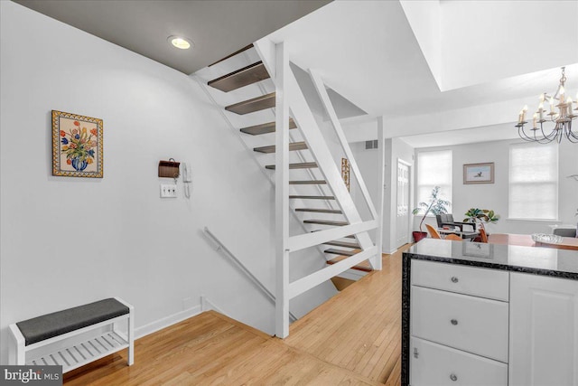 stairway with hardwood / wood-style flooring and an inviting chandelier