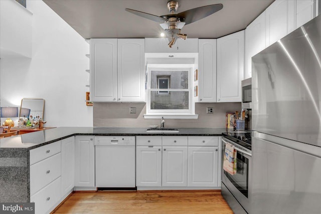 kitchen featuring white cabinets, stainless steel appliances, dark stone counters, and sink