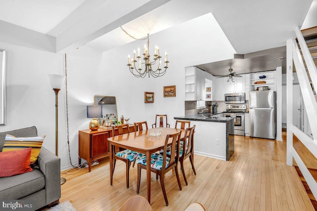 dining area featuring ceiling fan with notable chandelier, sink, and light hardwood / wood-style flooring